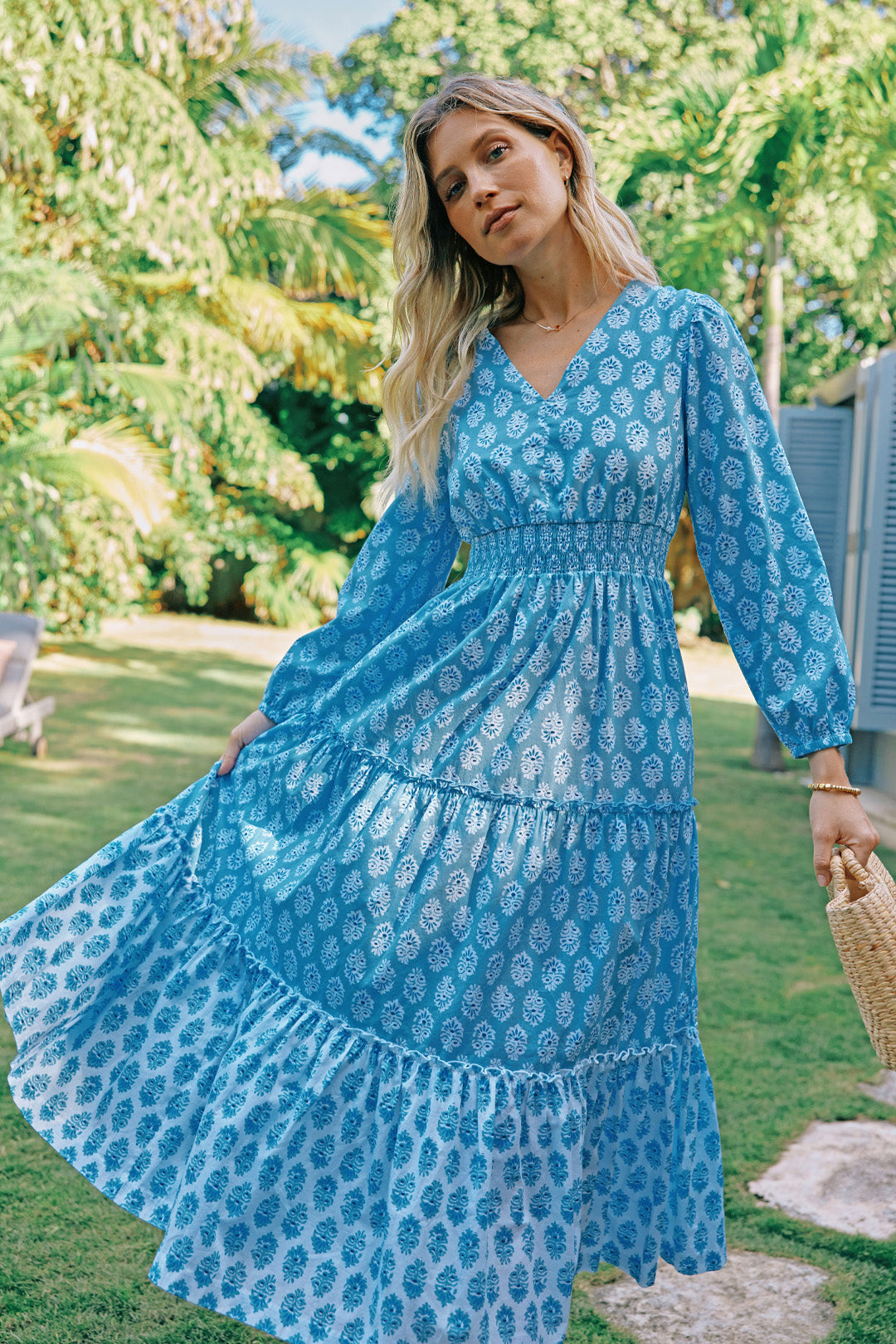 Woman in flowy, blue maxi dress in a garden.