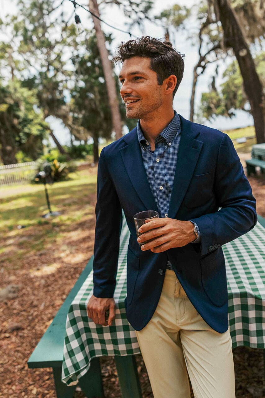 Man wearing navy blazer with khaki pants at an outdoor event in the fall.