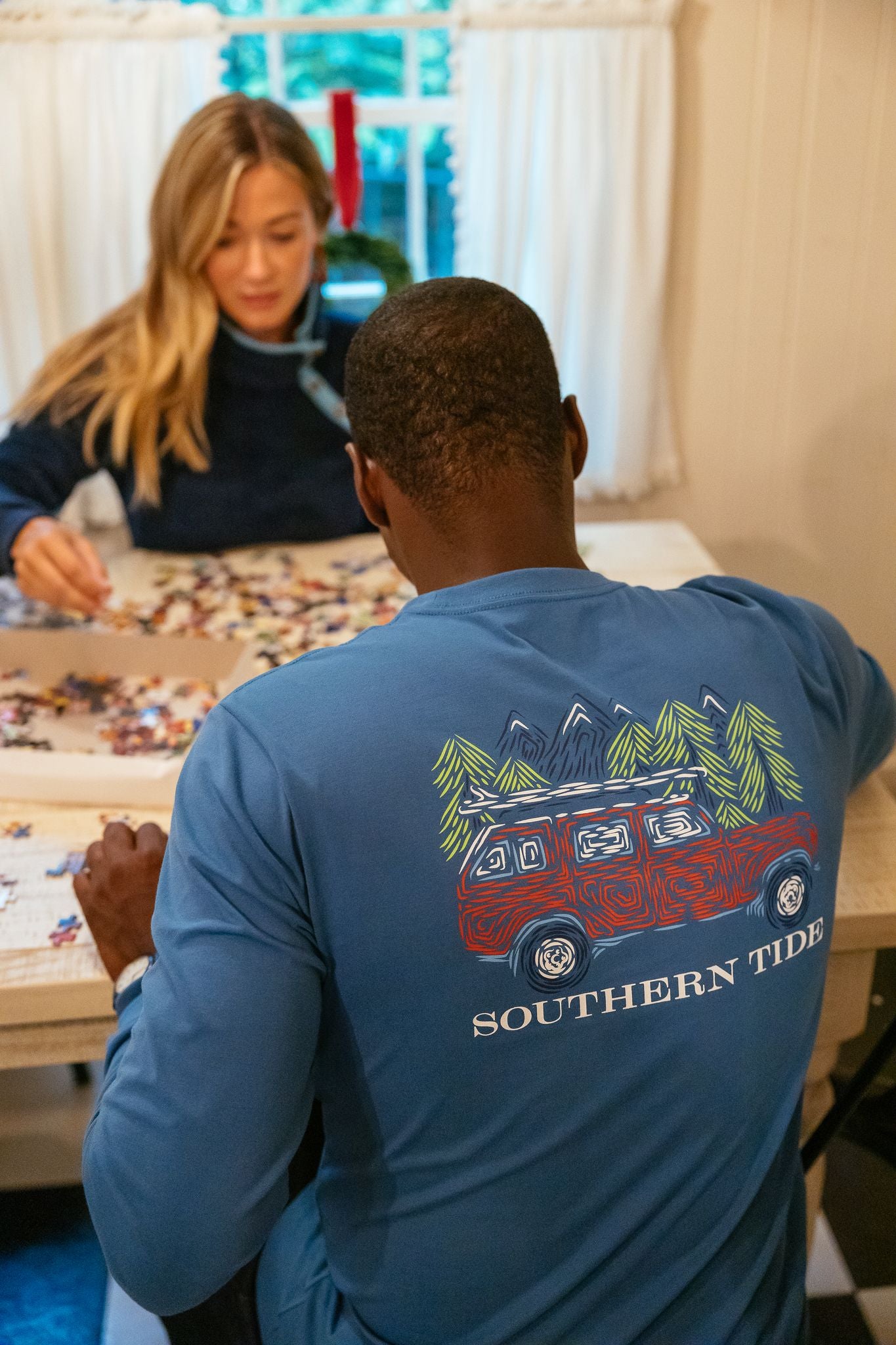 A man and woman in Southern Tide apparel working on a puzzle together. 
