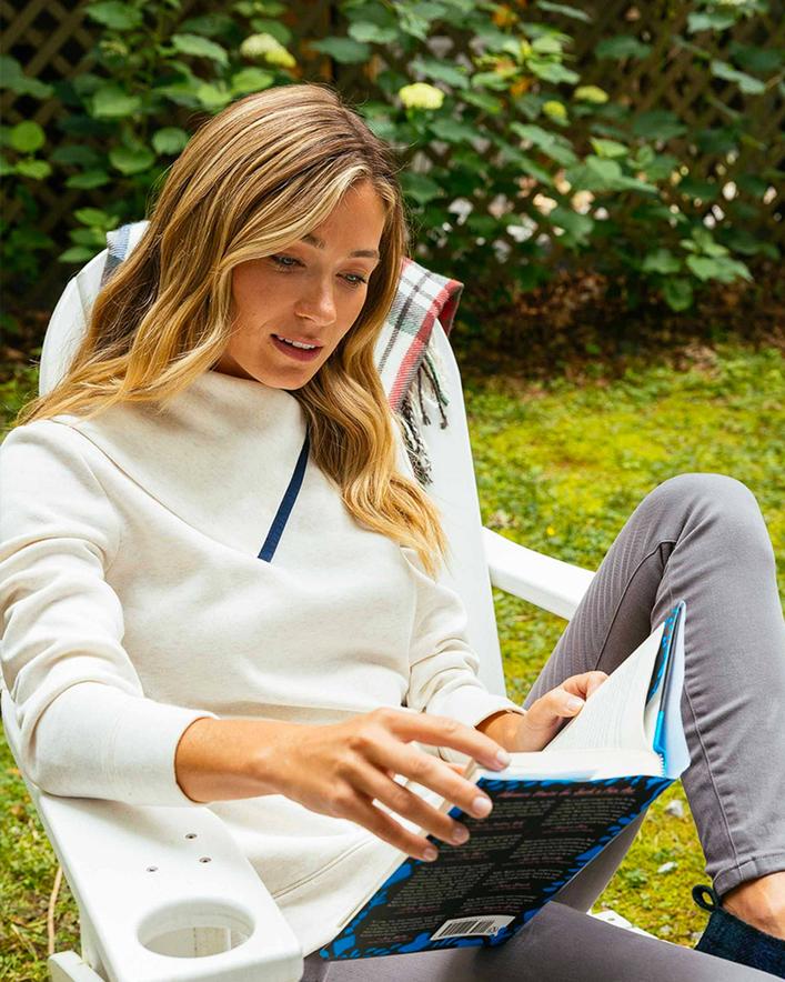 A women reading in a cozy pullover from Southern Tide. 