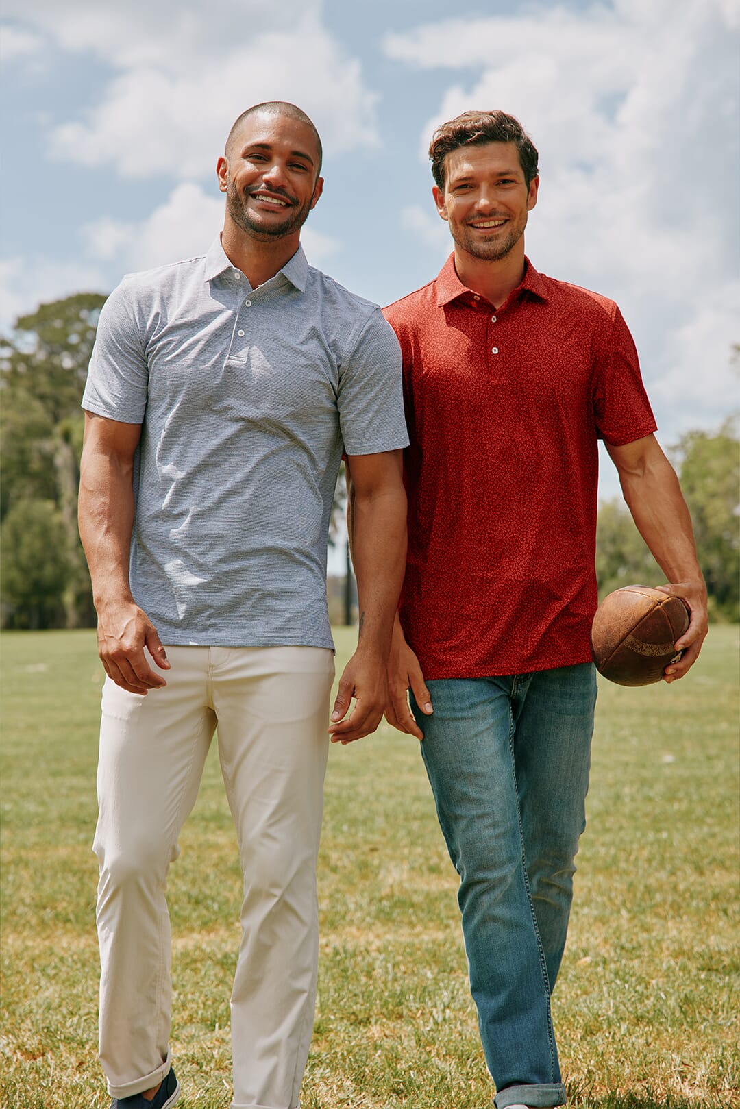 Two men in polos and pants ready for game day holding a football.