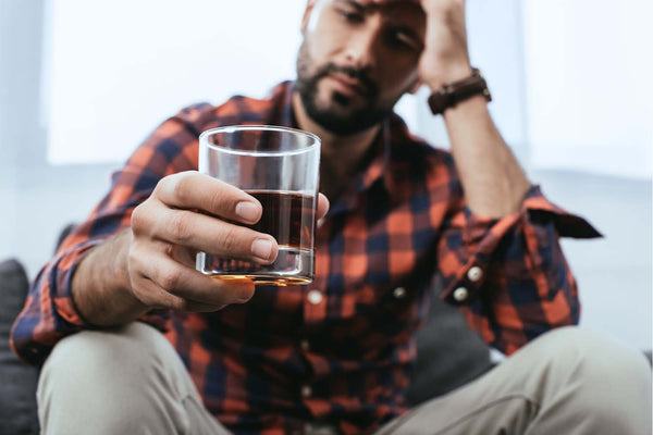 Man holding a small glass of alcohol