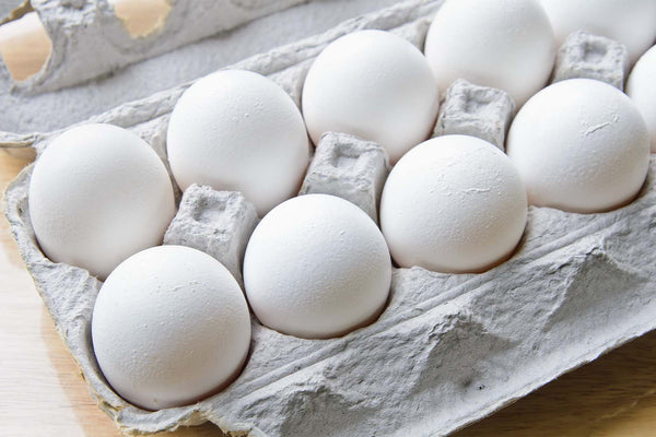A dozen white eggs sitting in their carton