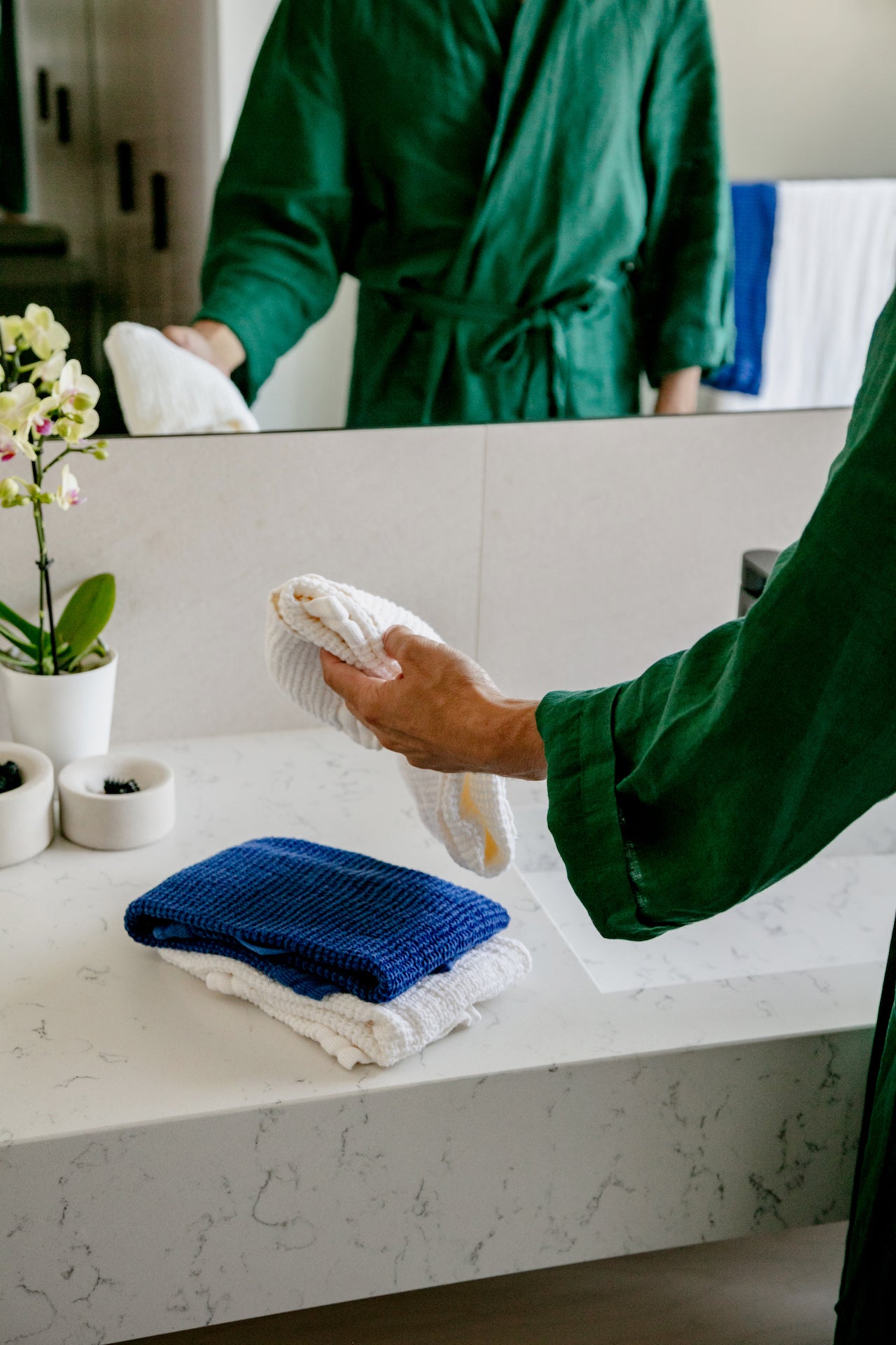 A man in a linen robe washing his face with waffle linen towels.