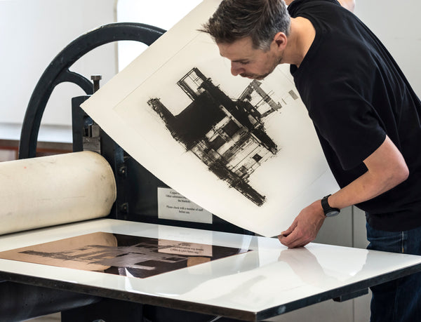 A photo of Artist Ian Chamberlain using a printing press