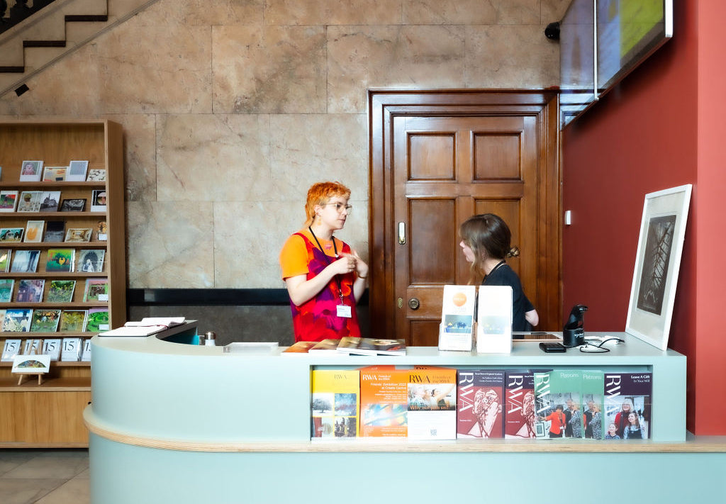 Two staff members behind the Welcome Desk