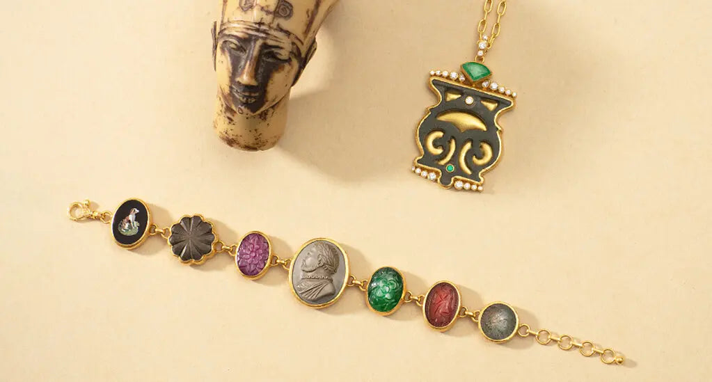 An elegant woman donning a black dress and gold jewelry, including a handcrafted bracelet with mixed stones, micro mosaics, ancient coins, and a lava cameo from the Antiquities Collection.