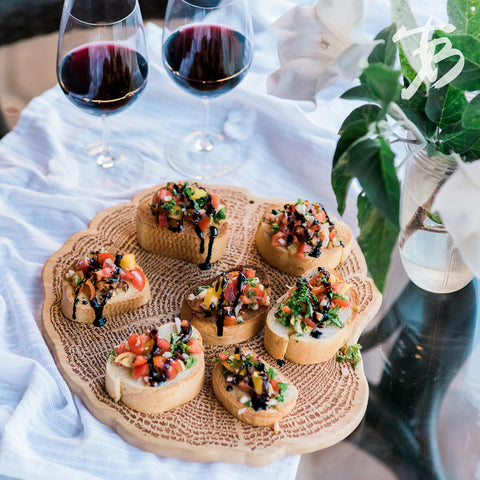 Bamboo charcuterie board with bruschetta and wine