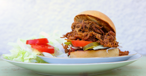 A plate with a pulled bbq sandwich.