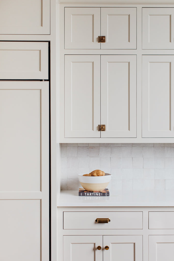 Plafond voûté dans la cuisine avec armoires beiges, îlot en bois teinté avec quartz, dosseret en tuile zellige.