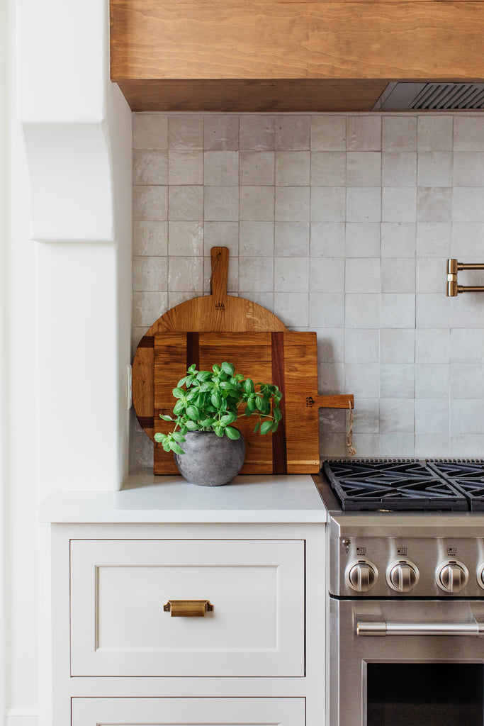 Dosseret en carrelage carré Cle zellige avec hotte en plâtre, comptoirs en quartz, armoires de cuisine couleur champignon.