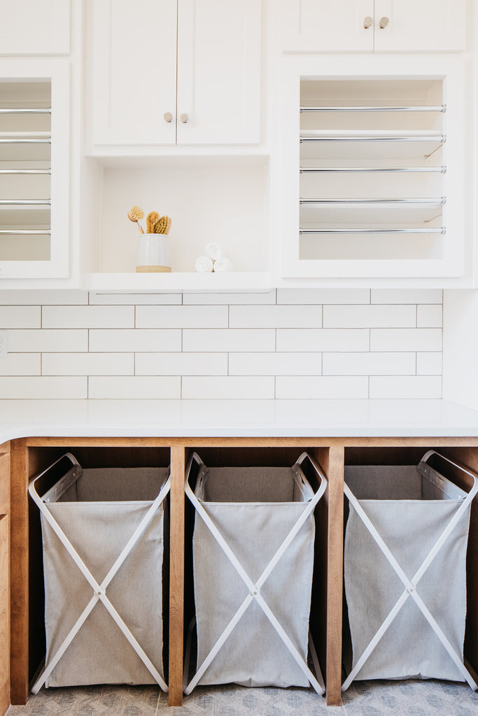 laundry room with white oak lower cabinetry and white upper cabinetry, tile floor, black window, and josh young art emma and eugene