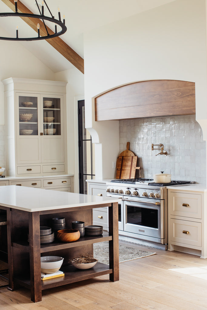 Plafond voûté dans la cuisine avec armoires beiges, îlot en bois teinté avec quartz, dosseret en tuile zellige.