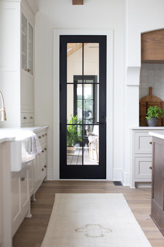 Plafond voûté dans la cuisine avec armoires beiges, îlot en bois teinté avec quartz, dosseret en tuile zellige.