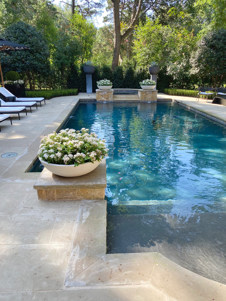 Outdoor Space by Melissa Gerstle Design  Classic, serene, and I loved the height of the landscaping planters to create a focal point at the end of the pool!  Interesting details like the pop of a design inside the umbrellas with a classic exterior.