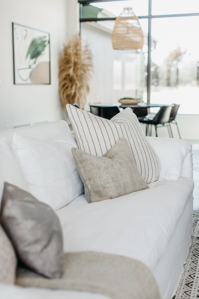 Beautiful, one-of-a-kind pillows adorn a white Cisco Brothers Donato Sofa.