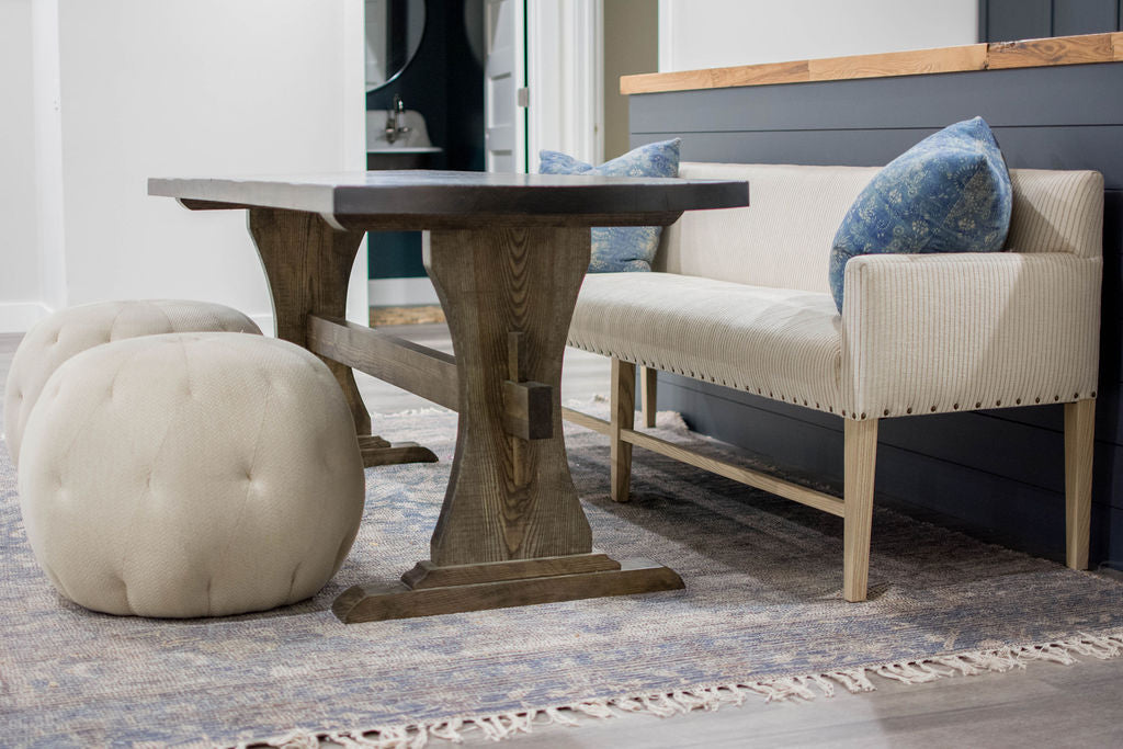 For basement dining, the client fell in love with a Verellen Thibaut dining bench paired with a handmade oval dining table, Cisco Brothers poufs, and a Loloi Cornelia rug