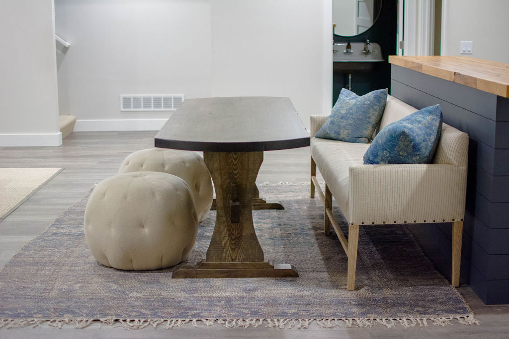 For basement dining, the client fell in love with a Verellen Thibaut dining bench paired with a handmade oval dining table, Cisco Brothers poufs, and a Loloi Cornelia rug from a different angle