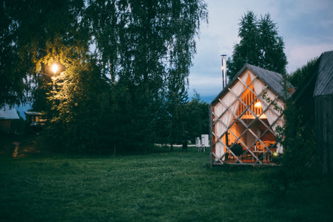 a small wooden house with a large greeny lawn with a light