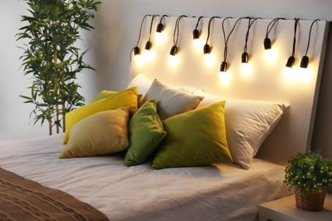 hanging light bulbs above the bed with a pant beside