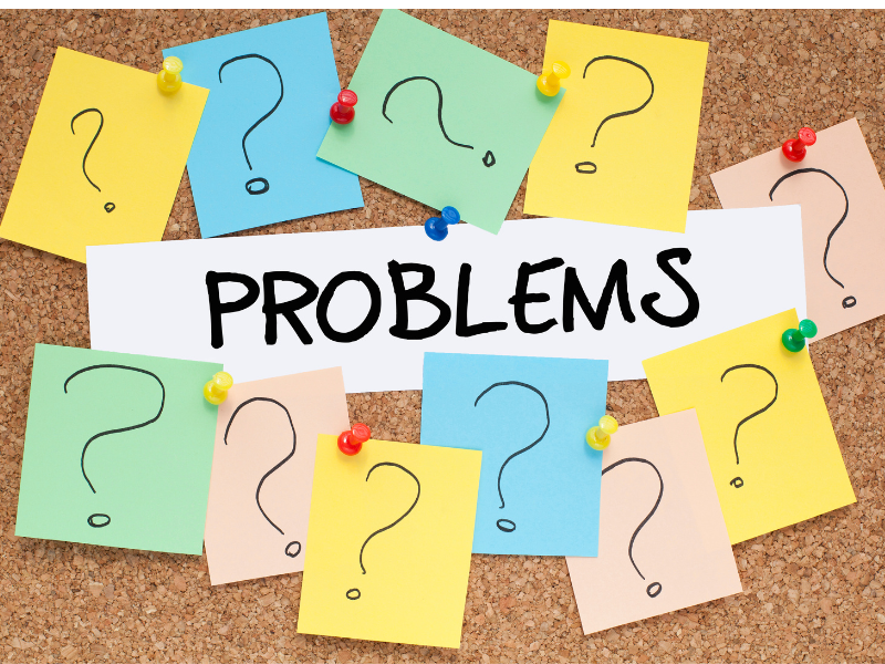 notepads with question marks surrounding a paper with "problems" written on it