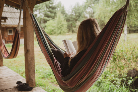 two hammocks with a girl on one of them reading a book