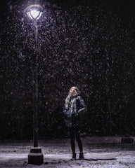 woman standing outside near a lamp post in a snowy evening