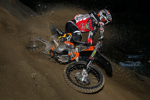 RISK Racing athlete turning his ktm in soft sand spraying roost. Wearing risk racings new red & black ventilate v2 motocross gear. 