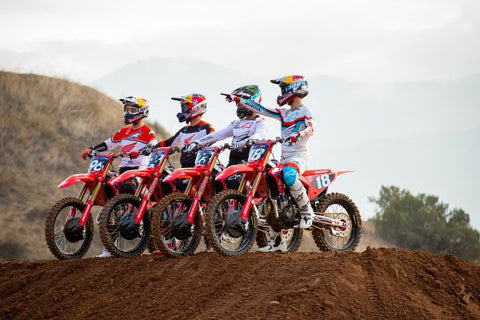 America's factory HRC Honda motocross team posing on the lip of a a supercross jump sitting on their 2022 race bikes