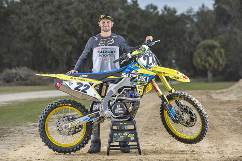 Chad Reed retired professional motocross/supercross racer standing behind a suzuki rmz 450 race bike