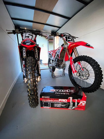 Two Honda dirt bikes mounted in lock-n-load pro transport device inside of an enclosed trailer.