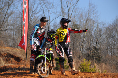 Two experienced riders assisting and instructing a younger rider. 