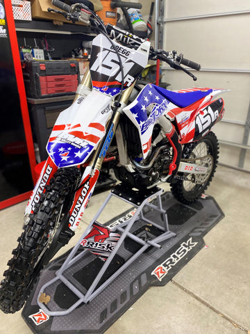 Motocross bike on risk racing's ride-on lift stand and factory pit floor mat