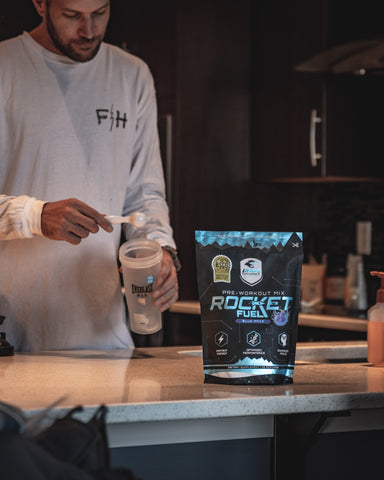 Person putting iRide blue raspberry rocket fuel in a shaker bottle before a workout.