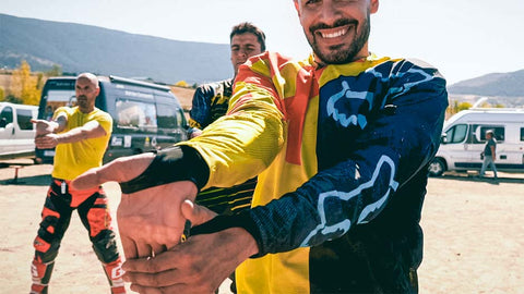 Group of motocross riders doing before riding to prepare their body. In this move they are pulling the fingers down with the palms turned out to stretch and open up the forearms. 