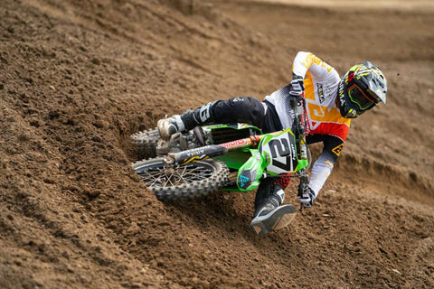 Rider in the hook of a rut on a motocross track. The inside foot of the rider is high to prevent dragging the foot and to keep the weight over the front end of the motorcycle. Elbows and feet are on the outside peg to have a stable riding position.