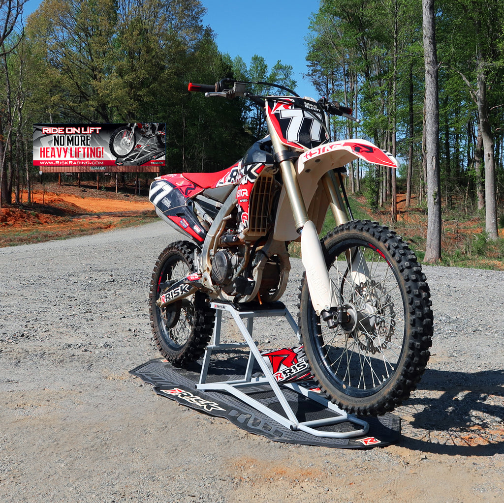 MX bike num 77 sitting on a RR1 Ride on mx lift stand on top of a pit mat all covered in Risk Racing emblems