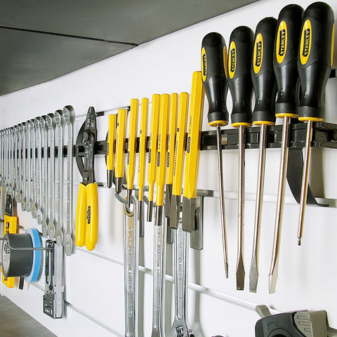 magnetic tool holder mounted on a wall with a variety of tools magnetically attached to it.