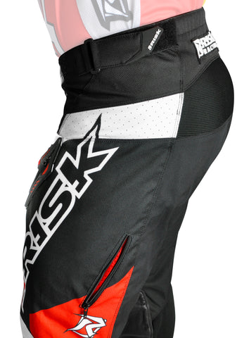 Risk racing's motocross gear has intake and exhaust zipper vents to allow cool air in and heat out. A model is posing from the side showing the risk racing exhaust vent the on the ventilate v2 mx pant