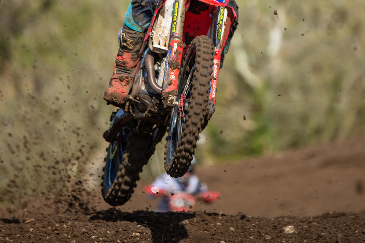 Racer de motocross laissant un saut vers la caméra. Super zoom sur les pneus. Les pneus plews vous ont été apportés par la course à risque.