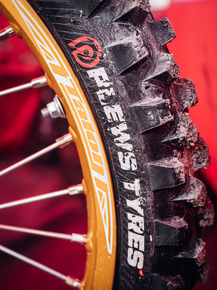 Close up vertical pic of a the Plews Tyres logo on the sidewall of a motocross bike.