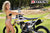 September's Risk Racing Moto Model Denna Lynn posing in various bikinis & Risk Racing Jerseys next to a dirt bike that's sitting on a Risk Racing ATS stand - Pose #7