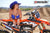 October's Risk Racing Moto Model Dani Hamilton posing in various bikinis and Risk Racing Jerseys next to a dirt bike that's sitting on a Risk Racing ATS stand - Pose #6