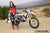 La modelo de moto de Risk Racing de octubre, Jessica Victorino, posa con varios bikinis y camisetas de Risk Racing junto a una moto de cross que está sentada en un soporte de Risk Racing RR1-Ride-On - Pose #28