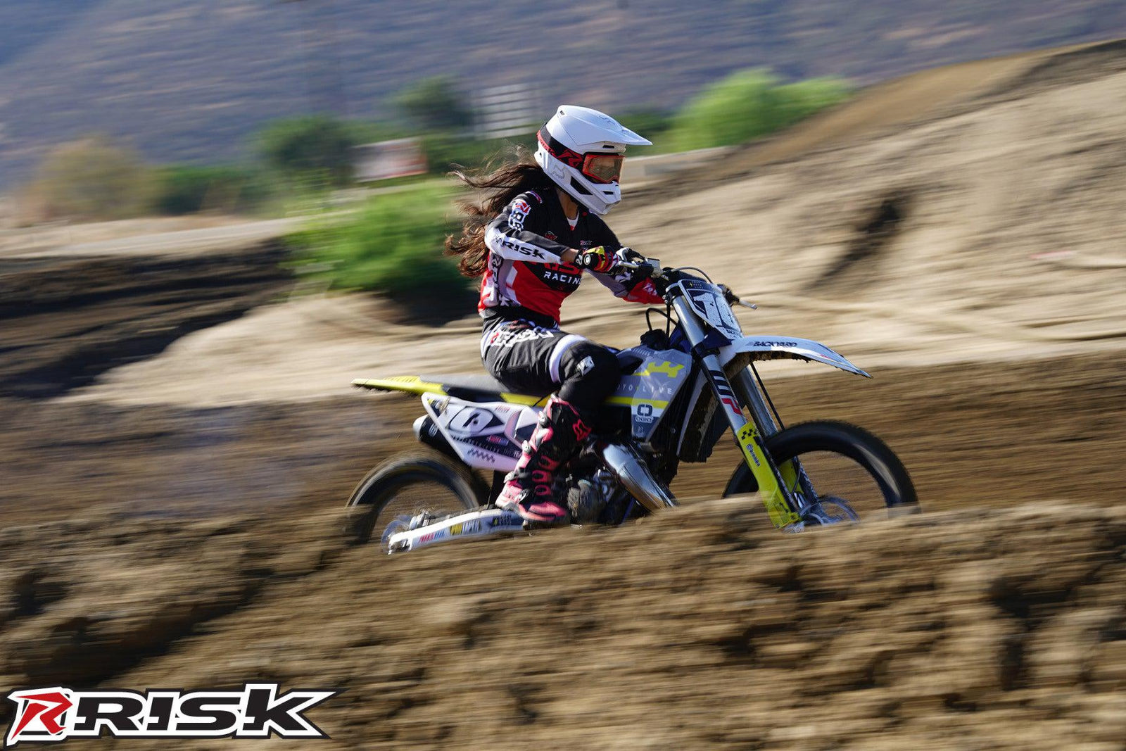 La modelo de moto de Risk Racing de octubre, Jessica Victorino, posa con varios bikinis y camisetas de Risk Racing junto a una moto de cross que está sentada en un soporte de Risk Racing RR1-Ride-On - Pose #32