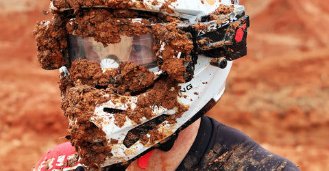 Motocross goggles covered in mud from the spray of another riders back wheel.