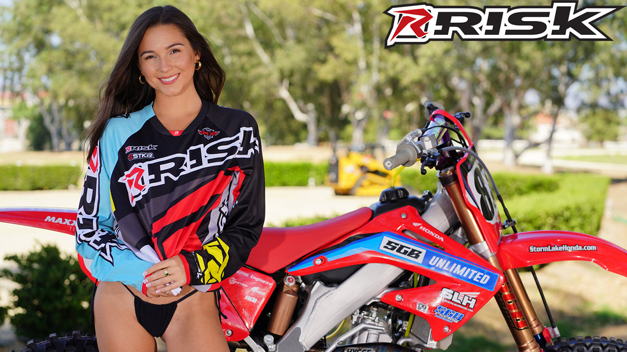 July's Risk Racing Moto Model Samantha Heady posing in various bikinis & Risk Racing Jerseys next to Alex Ray's Honda CR250R that's sidding on a Risk Racing ATS stand - Pose #36
