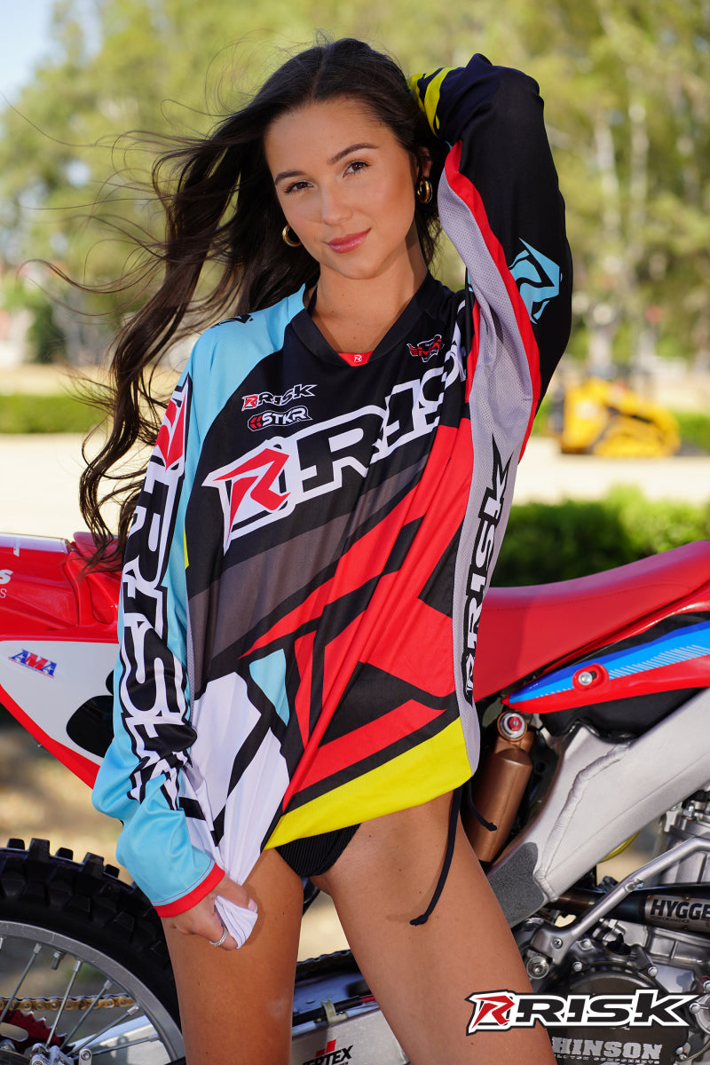 July's Risk Racing Moto Model Samantha Heady posing in various bikinis & Risk Racing Jerseys next to Alex Ray's Honda CR250R that's sidding on a Risk Racing ATS stand - Pose #37