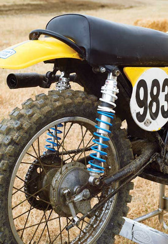 vintage dirt bike at a motocross track showing off the vintage dual rear shocks. 