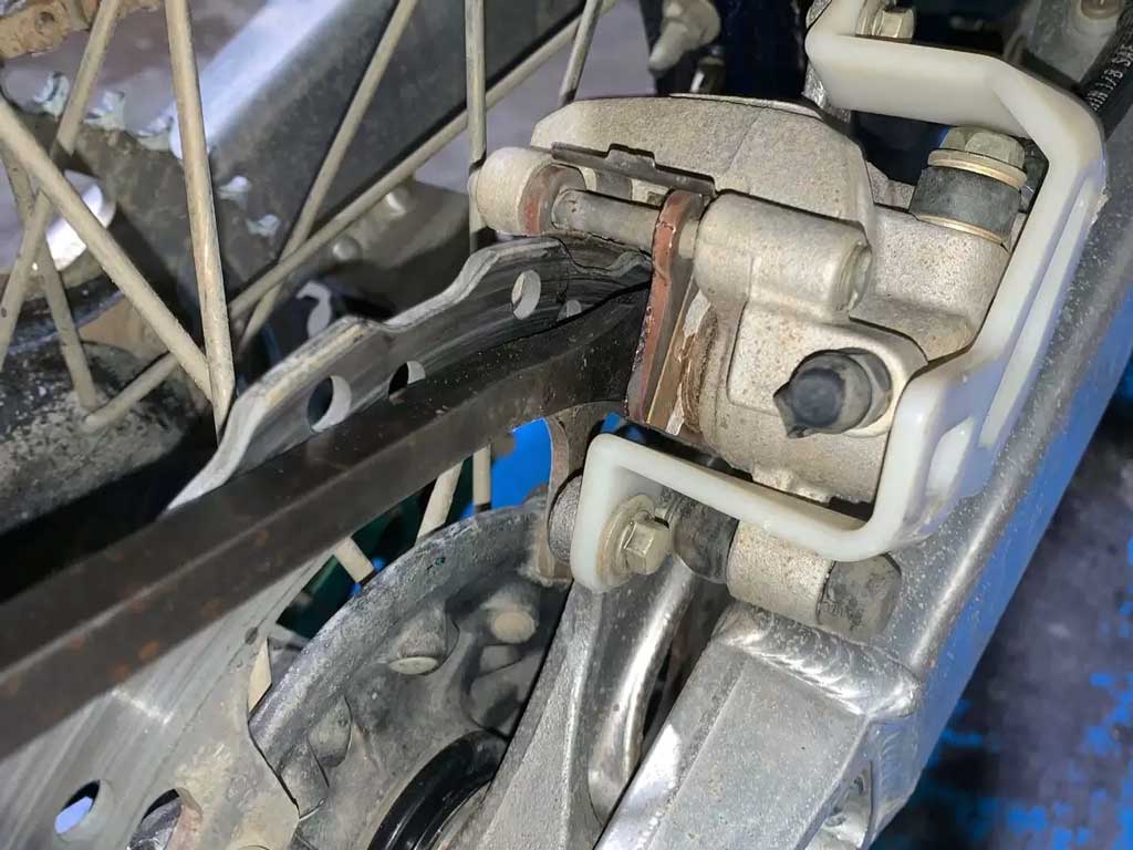 close up of a dirt bike brake system showing rotors pads and pistons
